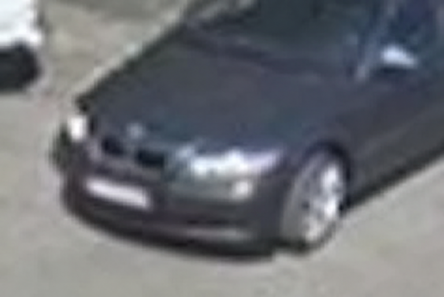 Low-resolution cropped frame of a dark sedan